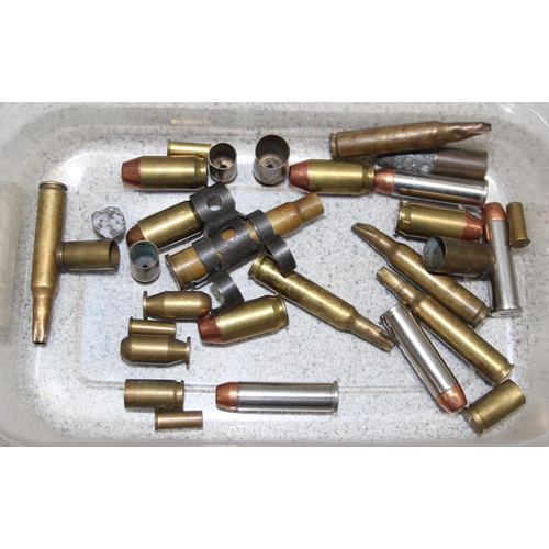 1404 - Qty of spent brass bullet casings and a muzzle suppressor