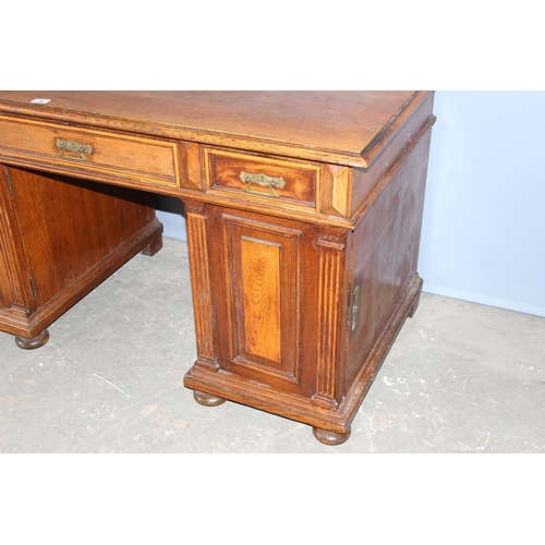 42 - An early 20th century oak pedestal desk with brass handles, approx 140cm wide