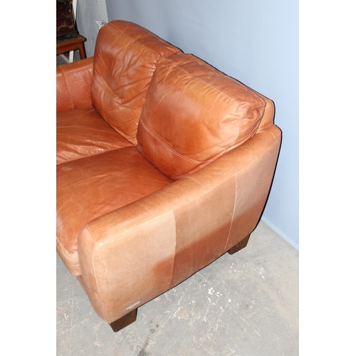 60 - An Italian tan leather 2 seater sofa with footstool by Sofitalia International