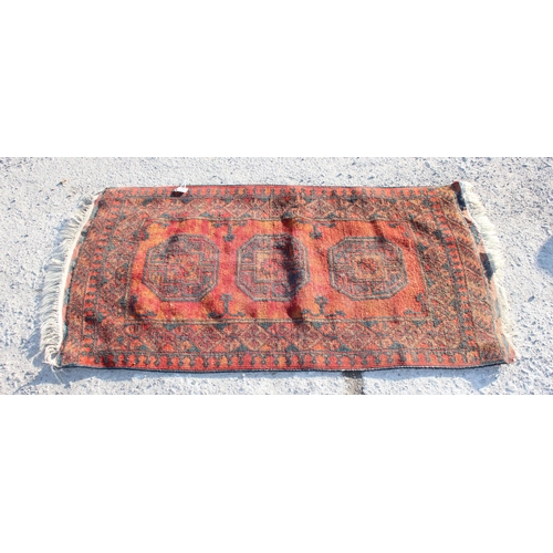 212 - A vintage hand made red ground Afghan rug with 3 gul, approx 154cm x 74cm