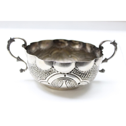 1066 - An unusual silver bowl with embossed decoration and 2 handles, possibly a quaich or wine taster, ind... 