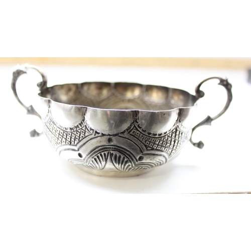 1066 - An unusual silver bowl with embossed decoration and 2 handles, possibly a quaich or wine taster, ind... 