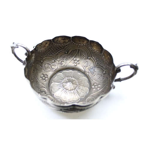 1066 - An unusual silver bowl with embossed decoration and 2 handles, possibly a quaich or wine taster, ind... 