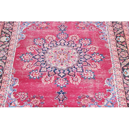 219 - A large vintage hand made Persian Mashhad rug, decorative red ground with arabesque border, approx 3... 