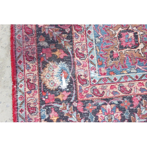 219 - A large vintage hand made Persian Mashhad rug, decorative red ground with arabesque border, approx 3... 