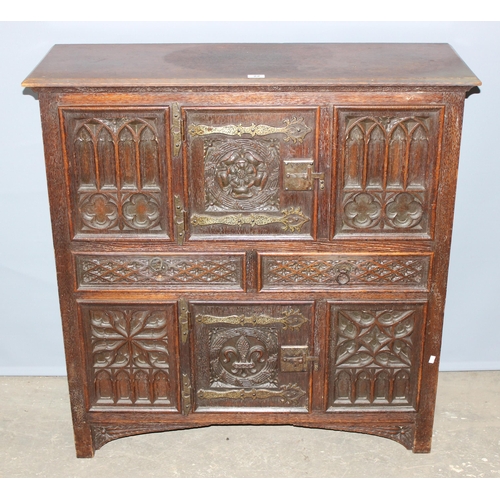 22 - A heavily carved 16th century style oak aumbry or livery cupboard, carved with the Tudor rose and a ... 