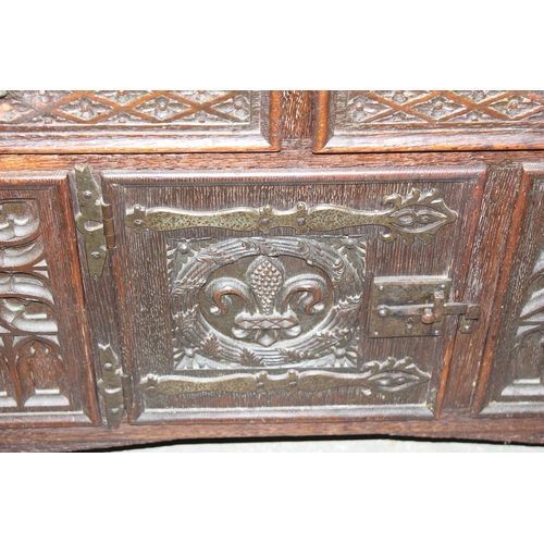 22 - A heavily carved 16th century style oak aumbry or livery cupboard, carved with the Tudor rose and a ... 