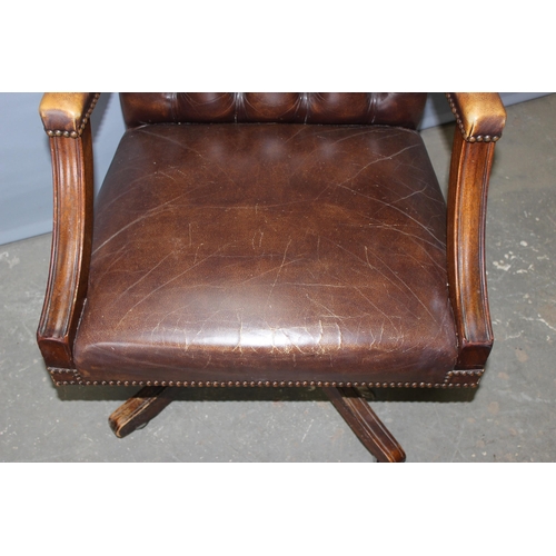 37 - An antique style Chesterfield button backed Captain's or office desk chair, in dark brown leather or... 