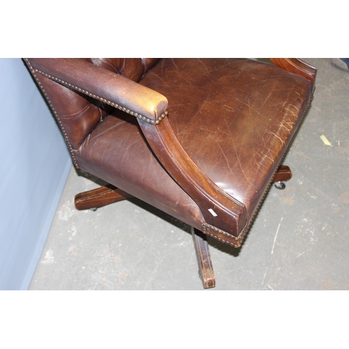 37 - An antique style Chesterfield button backed Captain's or office desk chair, in dark brown leather or... 