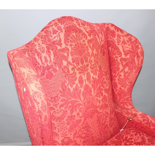 89 - A heavy wingback armchair with deep red patterned upholstery, recently recovered but believed to be ... 