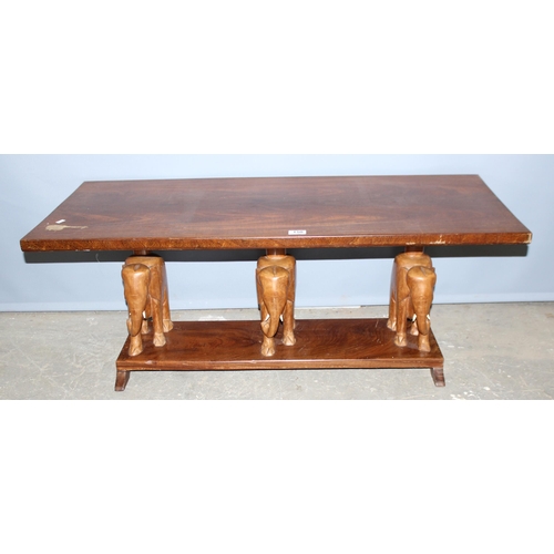 150 - A vintage wooden coffee table with carved elephant supports, approx 114cm wide