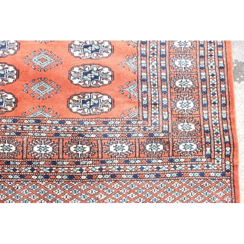 200 - A large vintage red ground Bokhara rug with 3 lines of gul, approx 240cm x 158cm