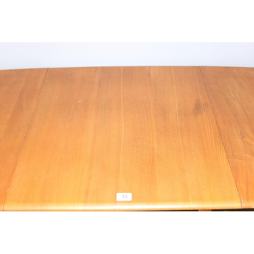 33 - A retro blonde Ercol drop leaf dining table with elm top, with blue & gold label, approx 140cm x 75c... 