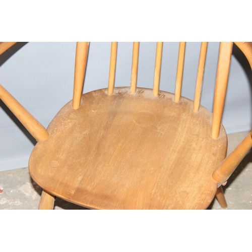 34 - A pair of blonde Ercol hoop backed carver chairs, one with remnants of a label, both with stamped ma... 