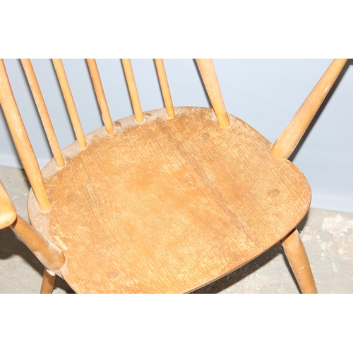 34 - A pair of blonde Ercol hoop backed carver chairs, one with remnants of a label, both with stamped ma... 