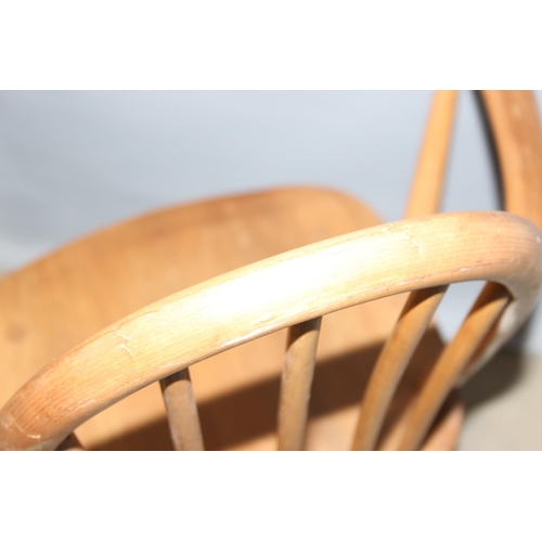 34 - A pair of blonde Ercol hoop backed carver chairs, one with remnants of a label, both with stamped ma... 