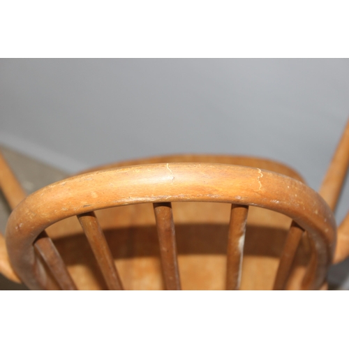 34 - A pair of blonde Ercol hoop backed carver chairs, one with remnants of a label, both with stamped ma... 