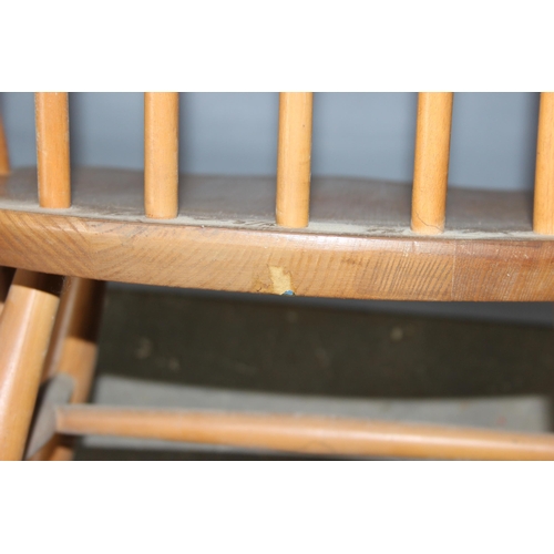 34 - A pair of blonde Ercol hoop backed carver chairs, one with remnants of a label, both with stamped ma... 