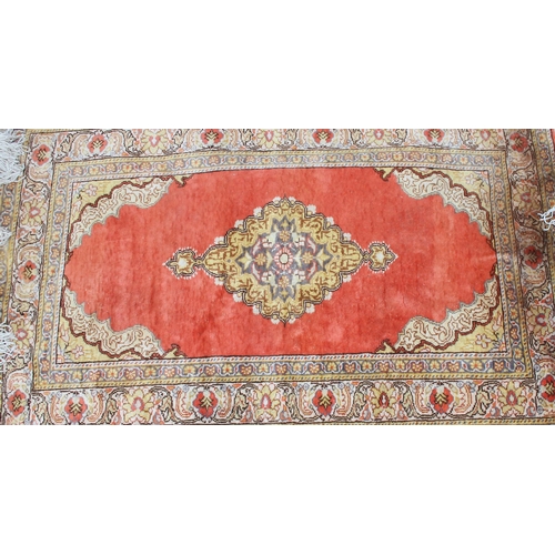 211 - A vintage hand made tangerine ground rug with decorative border, approx 142cm x 90cm