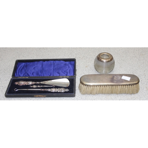 1036 - A silver backed brush, a silver mounted and ribbed glass match striker and a silver handled cased sh... 