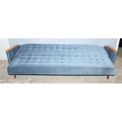 57 - A retro 1960's daybed or folding sofa with blue button backed upholstery and wooden arms, seemingly ... 