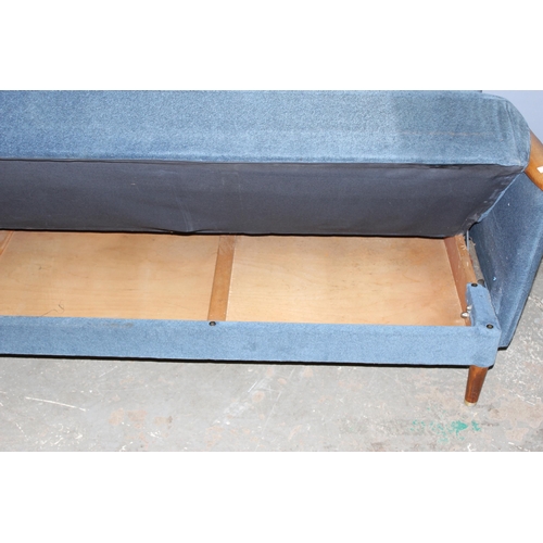 57 - A retro 1960's daybed or folding sofa with blue button backed upholstery and wooden arms, seemingly ... 