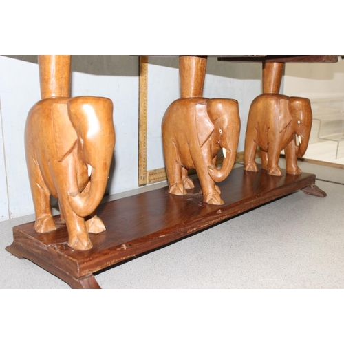 144 - A vintage West African wooden coffee table with carved elephant supports, approx 114cm wide