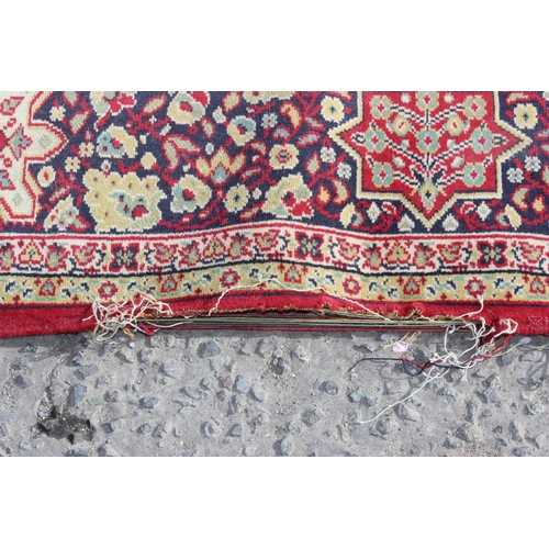 220 - An extremely large decorative red ground rug, approx 380cm x 270cm