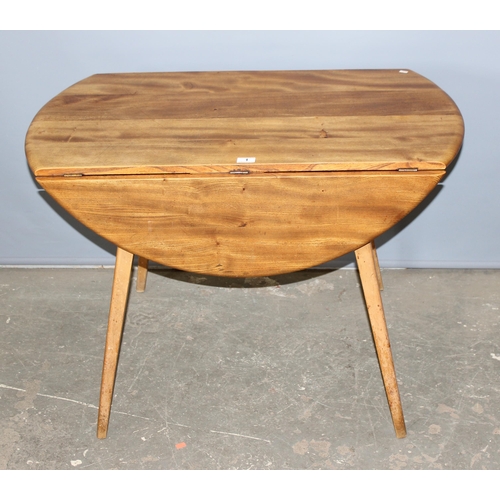 1 - A retro blonde Ercol dropleaf dining table, approx 141cm x 72cm when folded down, bearing partial la... 