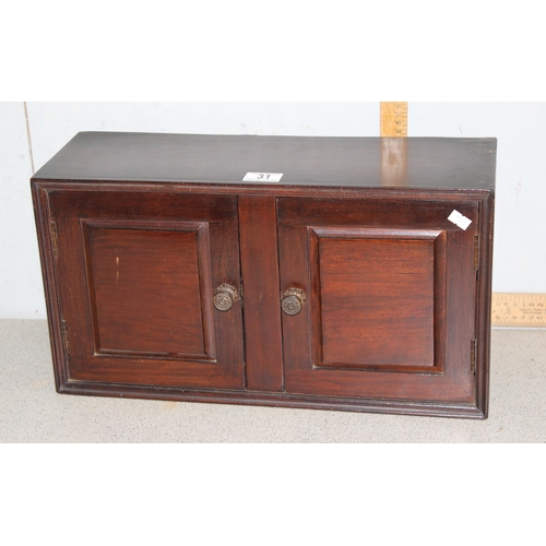 31 - A small mahogany table top 2 door cupboard, approx 48cm wide x 26cm tall