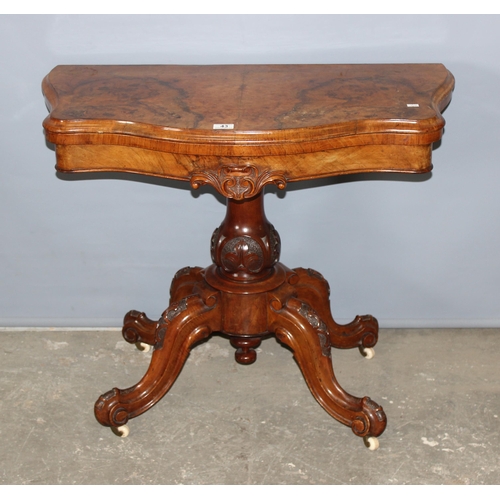 43 - A 19th century walnut folding card table with deep carved details, standing on carved pillar stand a... 