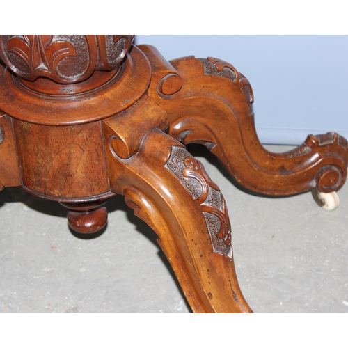 43 - A 19th century walnut folding card table with deep carved details, standing on carved pillar stand a... 