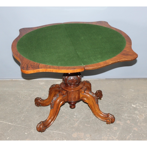 43 - A 19th century walnut folding card table with deep carved details, standing on carved pillar stand a... 