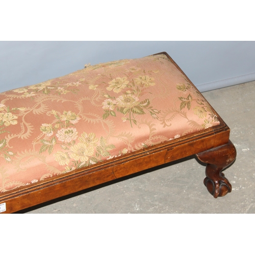 60 - An antique long low stuffed and upholstered foot stool standing on ball and claw feet, approx 100cm ... 