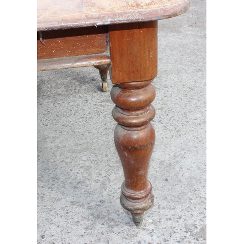 105 - A large antique dining table with pine top and mahogany base, approx 150cm x 130cm