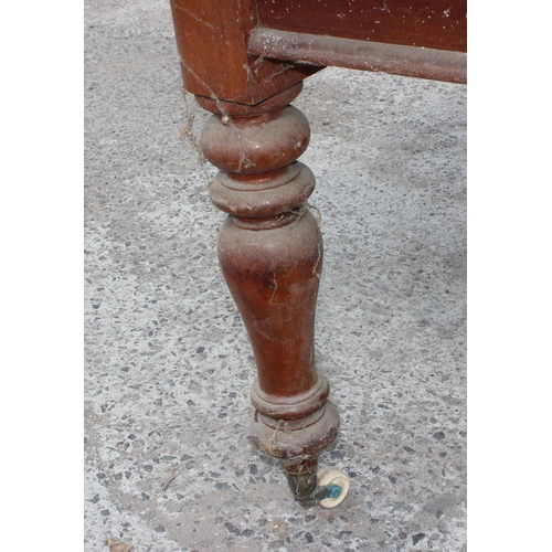 105 - A large antique dining table with pine top and mahogany base, approx 150cm x 130cm