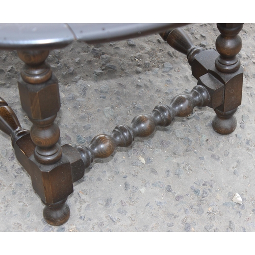 128 - An Ercol dark finish drop leaf table with bobbin turned legs, approx 106cm x 92cm