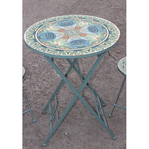 312 - A metal garden bistro set with 2 chairs, the table and chairs with colourful glazed pottery inserts,... 