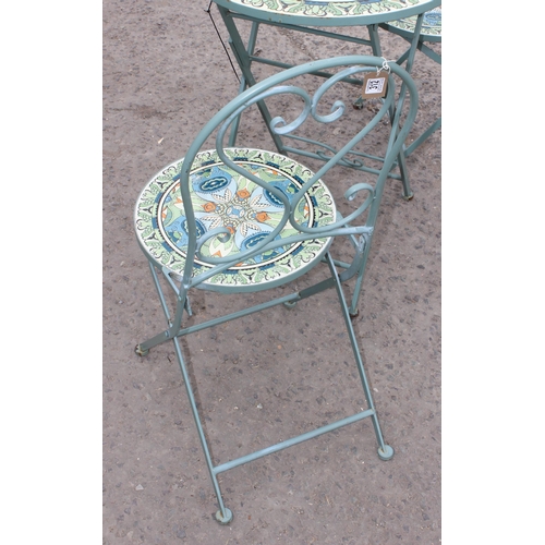 312 - A metal garden bistro set with 2 chairs, the table and chairs with colourful glazed pottery inserts,... 