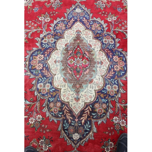 205 - A large decorative red ground rug with arabesque border, approx 400cm x 290cm