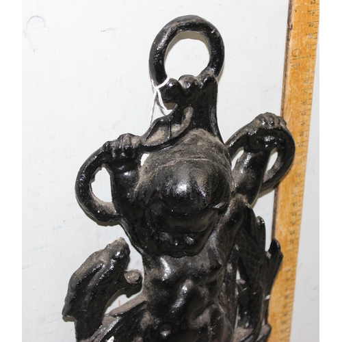 290 - An antique style cast iron door stop formed as a cherub with a dragon, approx 46cm tall