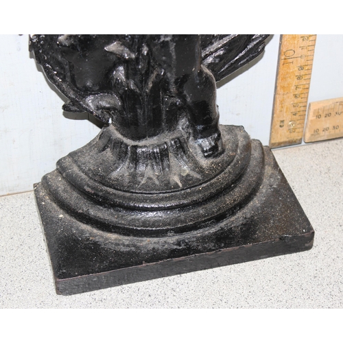 290 - An antique style cast iron door stop formed as a cherub with a dragon, approx 46cm tall