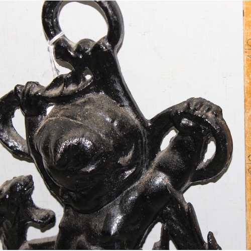 290 - An antique style cast iron door stop formed as a cherub with a dragon, approx 46cm tall