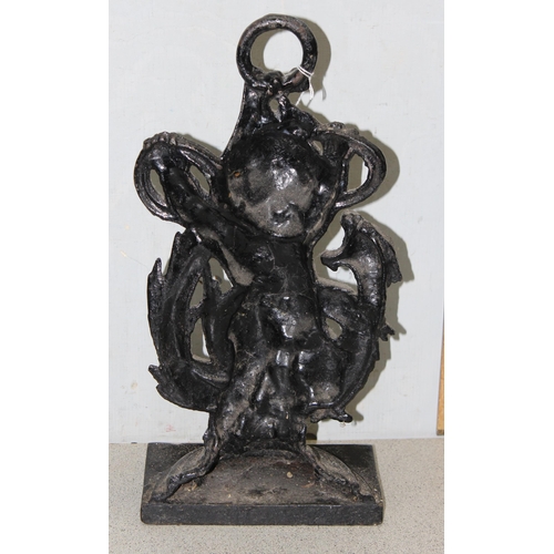 290 - An antique style cast iron door stop formed as a cherub with a dragon, approx 46cm tall