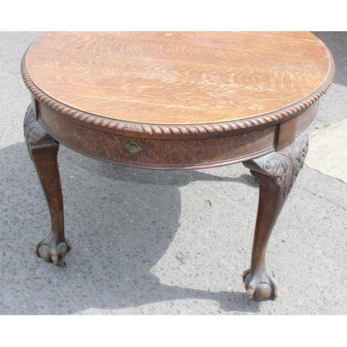 47 - An early 20th century oak wind out dining table with impressively carved paw feet and rope twist bor... 