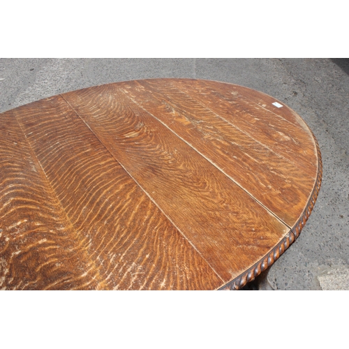 47 - An early 20th century oak wind out dining table with impressively carved paw feet and rope twist bor... 