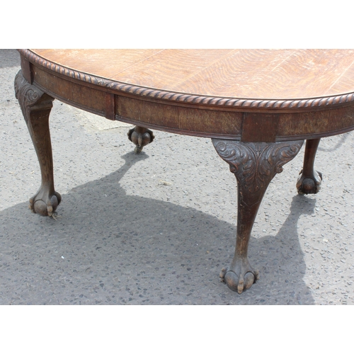 47 - An early 20th century oak wind out dining table with impressively carved paw feet and rope twist bor... 