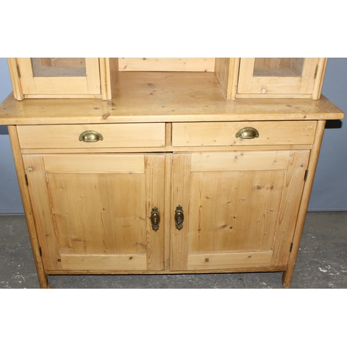 4 - A large antique pine kitchen dresser with 3 glazed doors over 2 drawers with brass cup handles over ... 