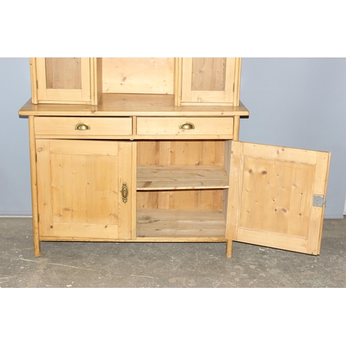 4 - A large antique pine kitchen dresser with 3 glazed doors over 2 drawers with brass cup handles over ... 