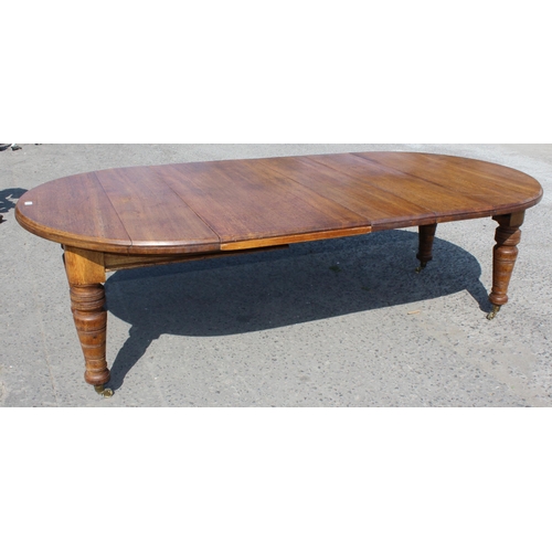 91 - An antique oak extending dining table with heavy turned legs and brass castors, 2 extra leaves, appr... 